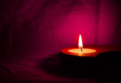 A candle burning in front of purple fabric